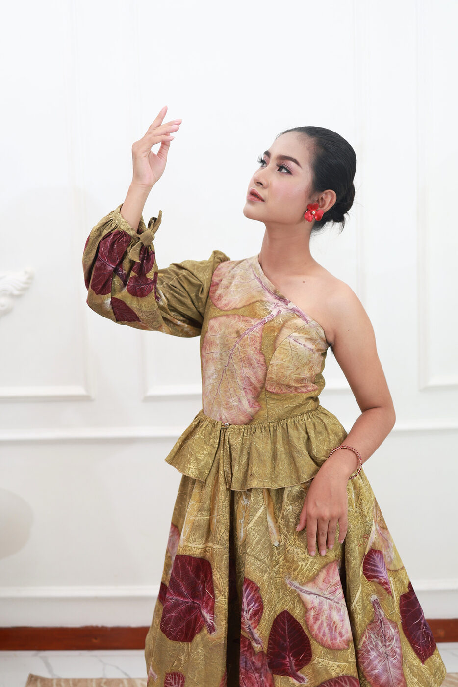 Model in a gold and burgundy leaf-print one-shoulder gown