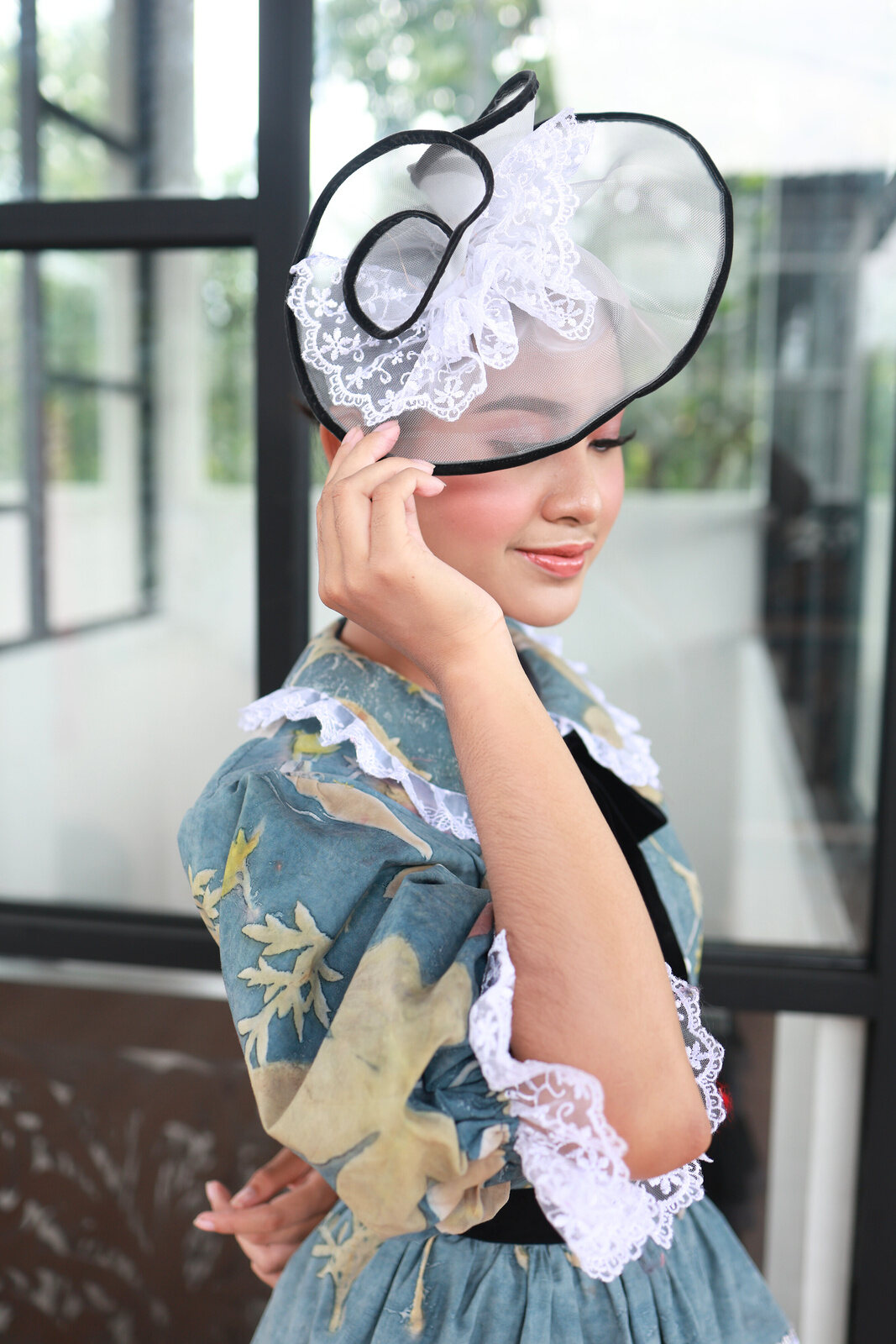 Model in a blue eco-print outfit wearing a lace fascinator